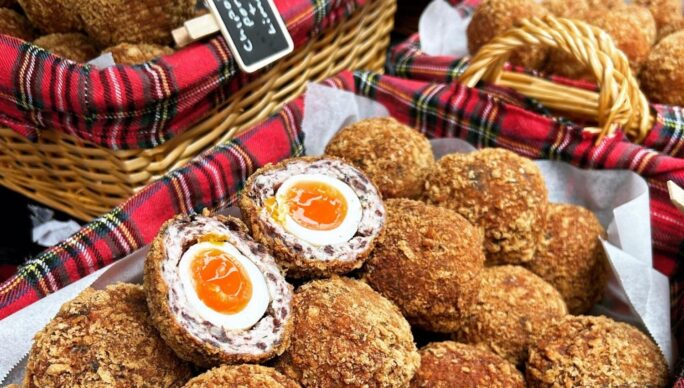 Scotch eggs treat selection for sale on a table top.
