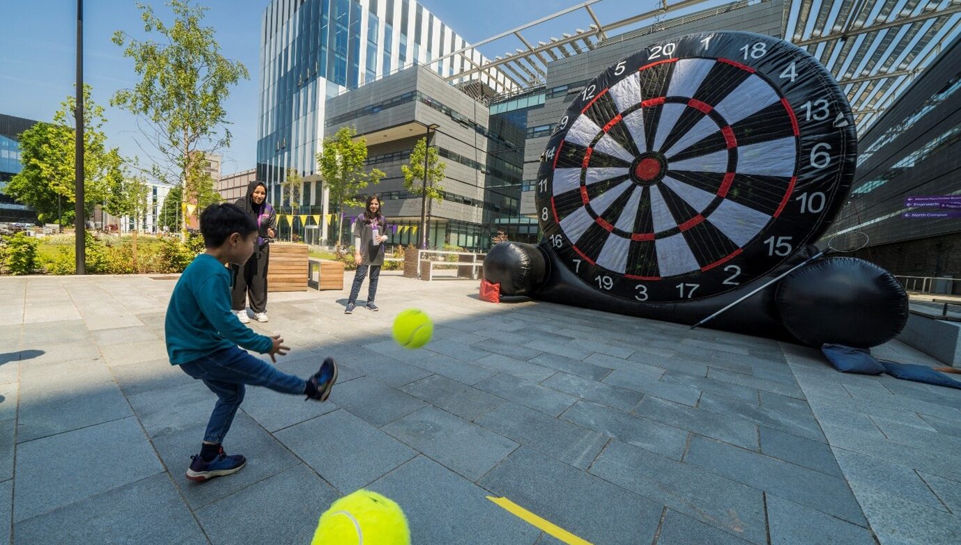 Image of child kicking a yellow football at a large inflatable target